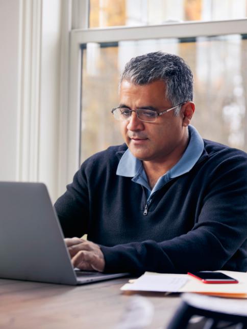 Man sitting at table typing on laptop